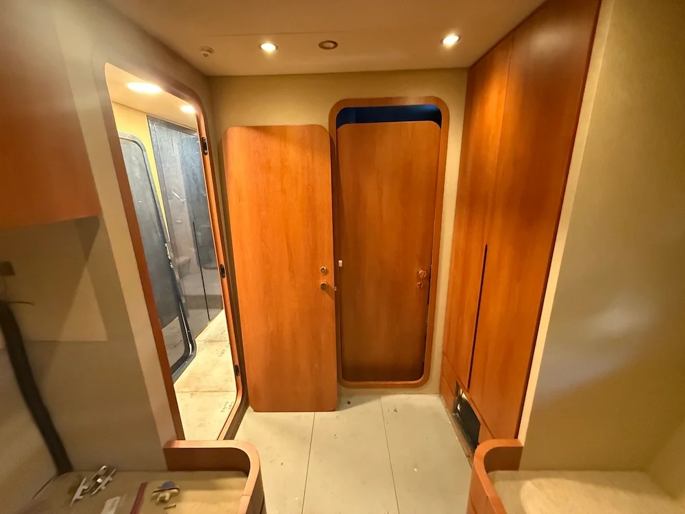 Wooden doors and cabinetry inside a RV or camper, with a sliding glass door leading outside and some small objects on a table.