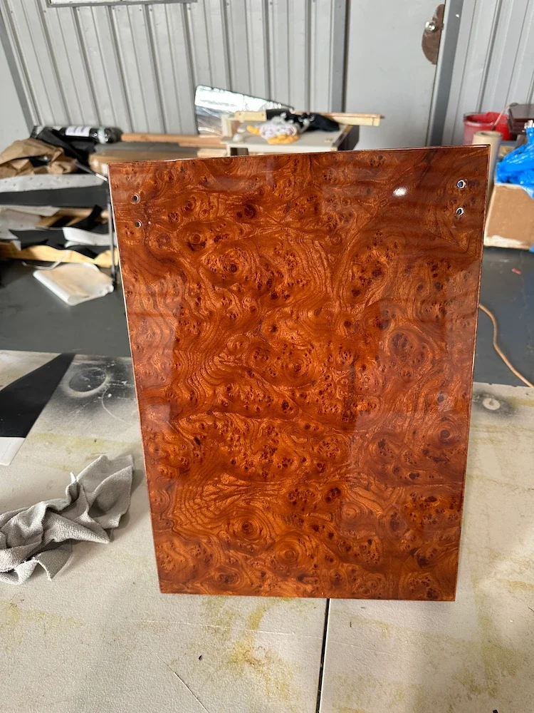 A polished piece of wood with a rich, swirling grain pattern standing upright on a work table.