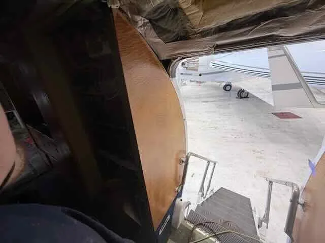 View of an airplane door with portable staircase leading outside onto the tarmac, partially covered by a curtain or curtain-like material.