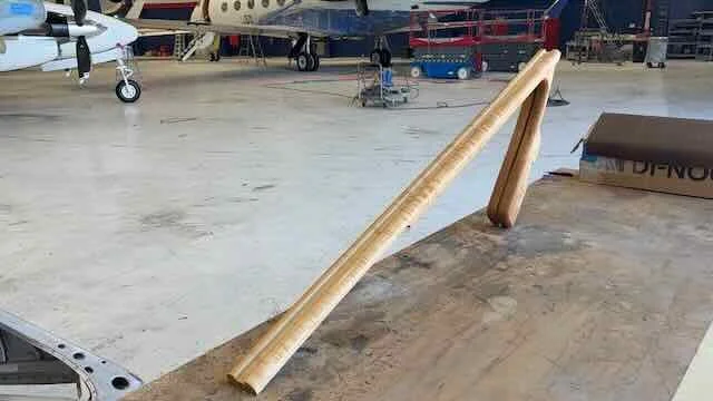 A wooden ramp constructed from two long wooden planks leaning against a surface inside an airplane hangar.