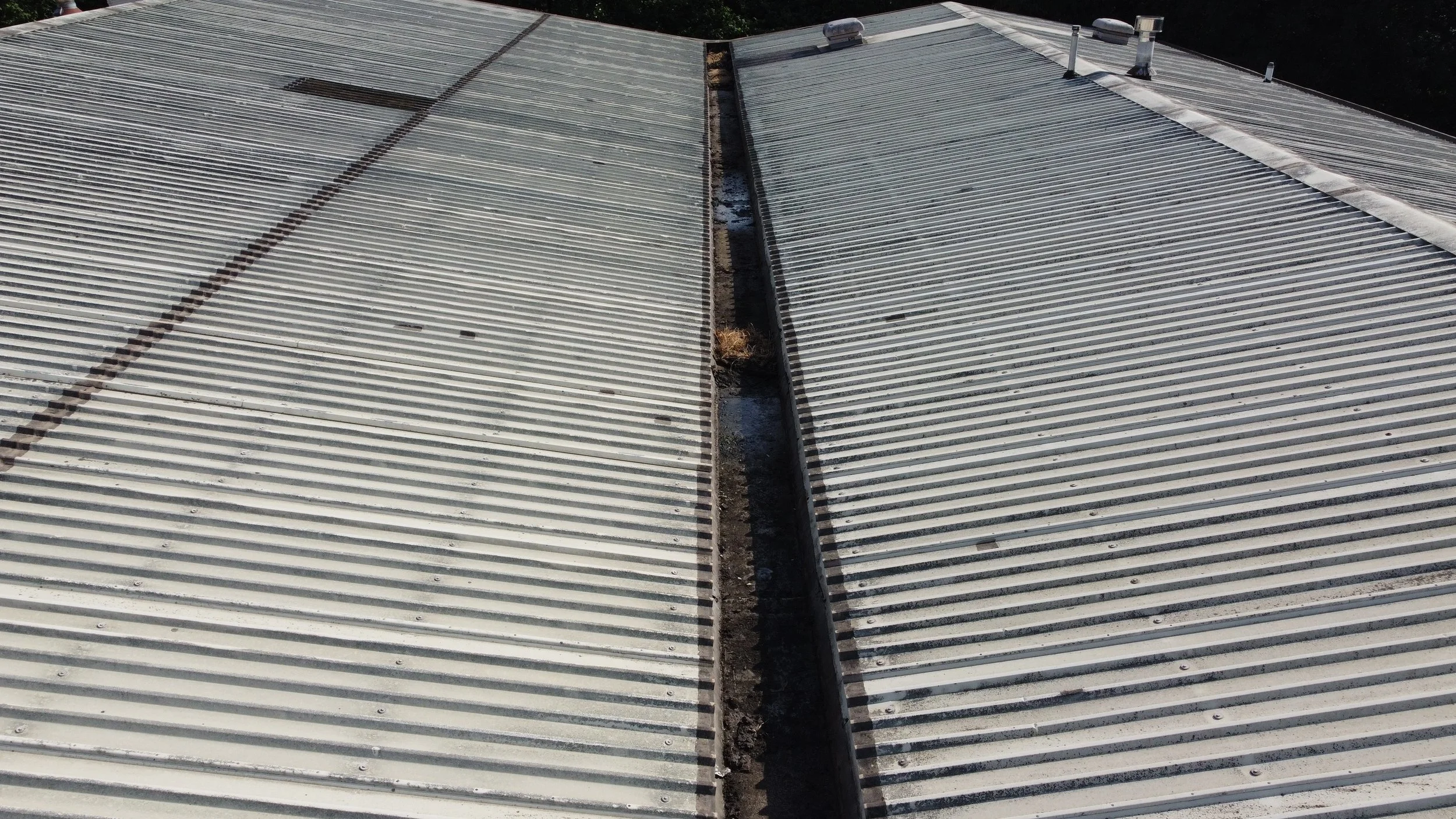 Two rooftops with metal corrugated roofing separated by a narrow gap - Roof/guttering inspection drone survey