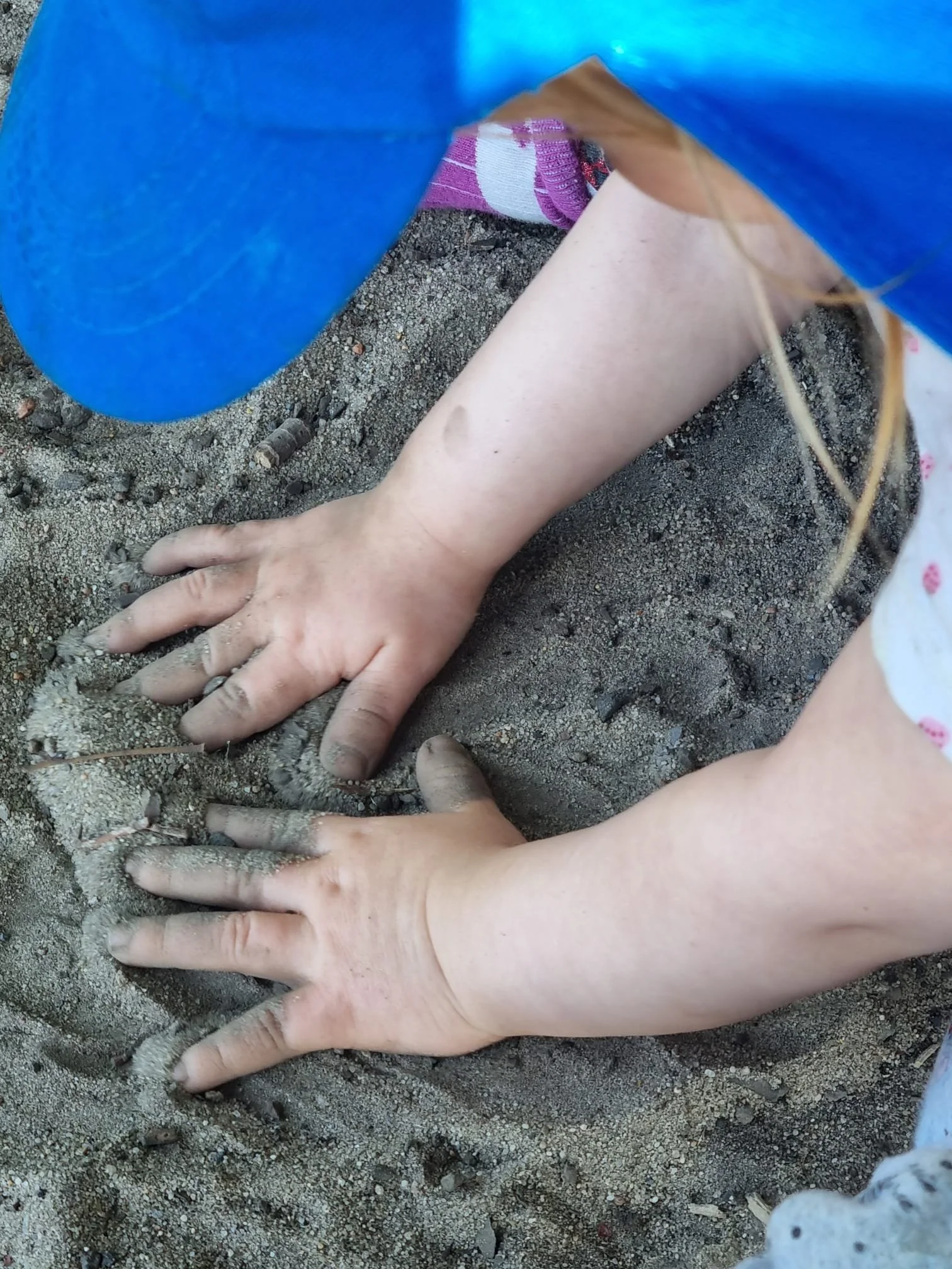 Menschen graben im Sand mit den Händen. Es ist Sand auf dem Boden. Es ist ein blauer Gegenstand, ein Faden und ein bisschen Kleidung sichtbar.