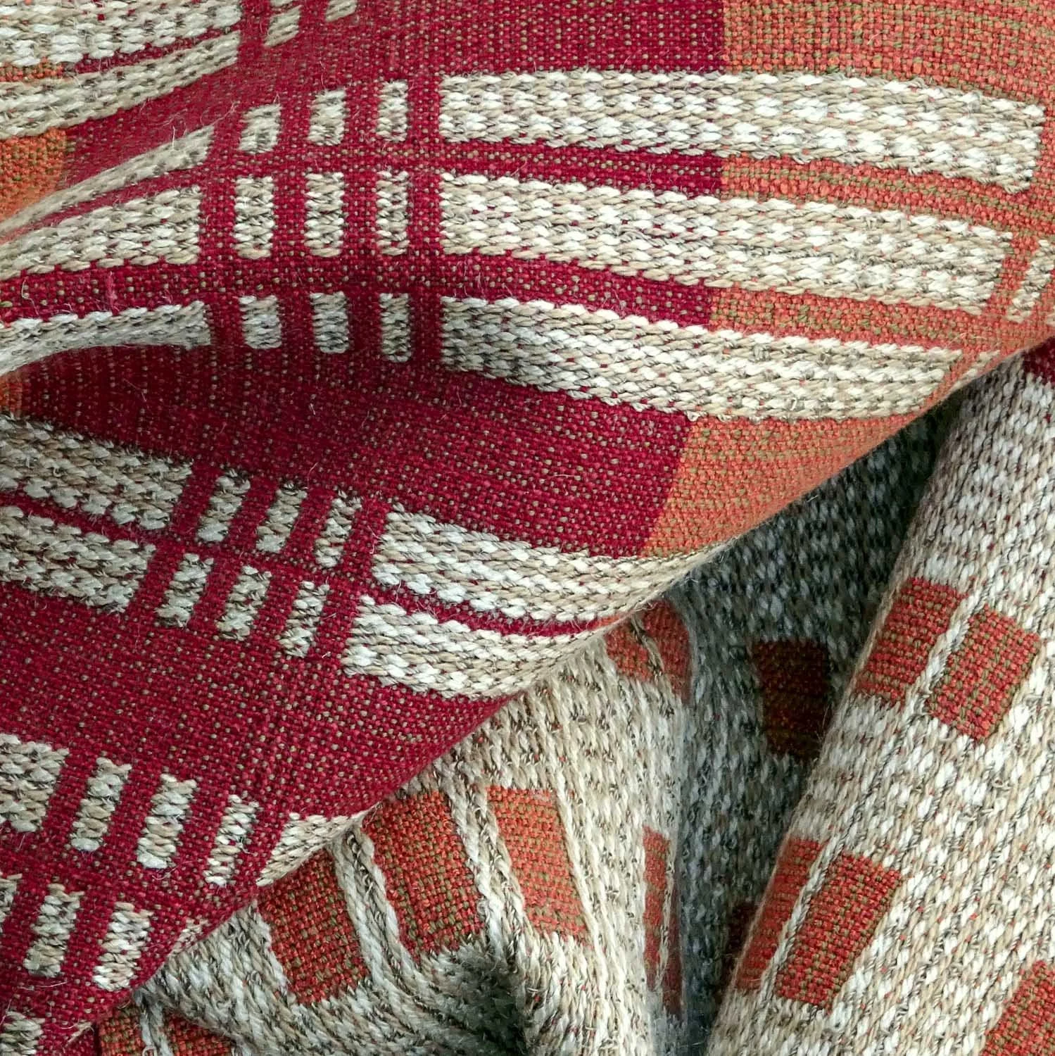 Close-up of handwoven fabric with a geometric pattern in red, beige, and orange tones. Crafted by Karen Donde of Asheville, NC.


