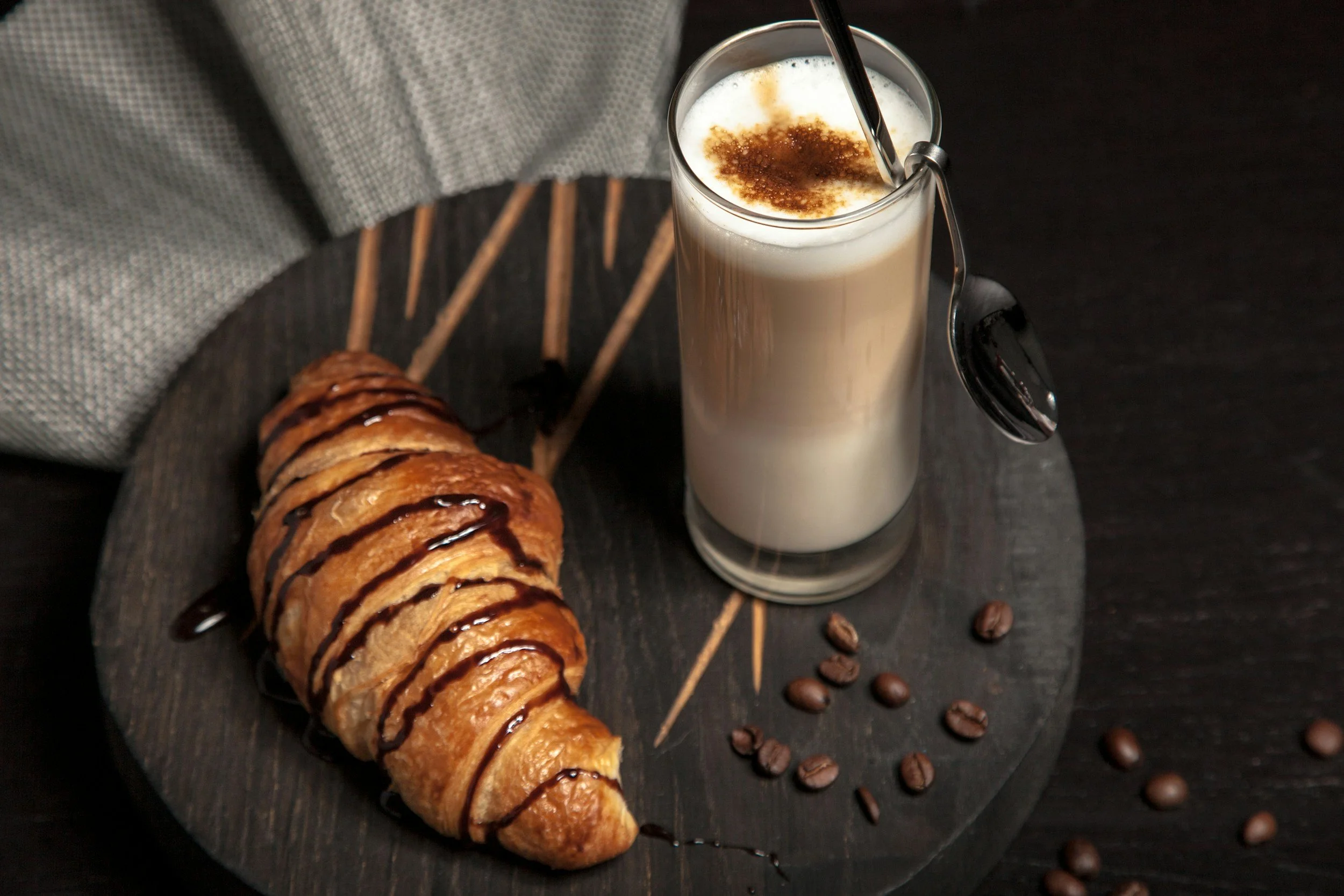 Un croissant garni de chocolat avec un grand verre de lait mousseux, décoré avec de la cannelle