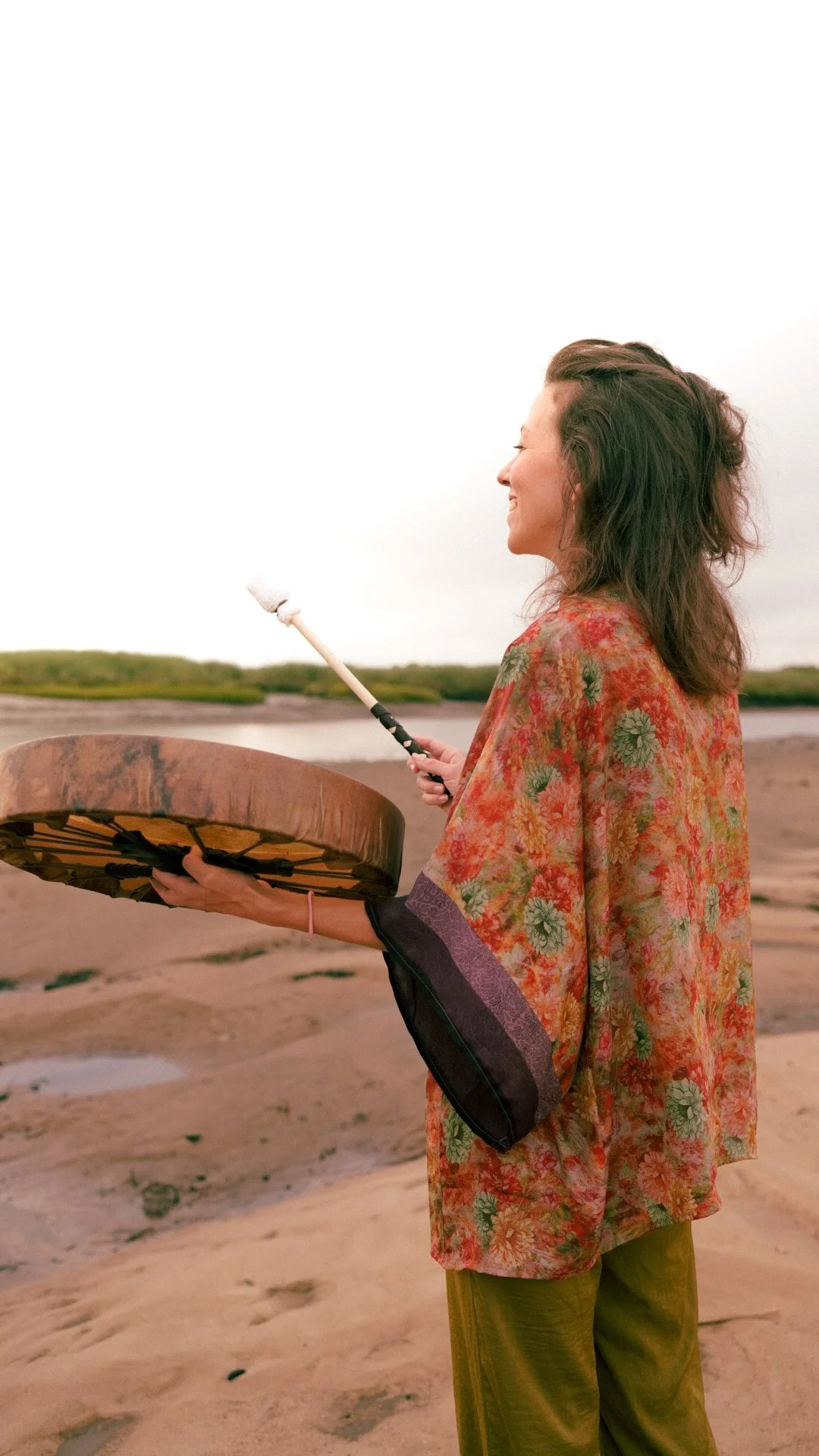 Éloïse tenant un tambour de danse chamanique face à la baie