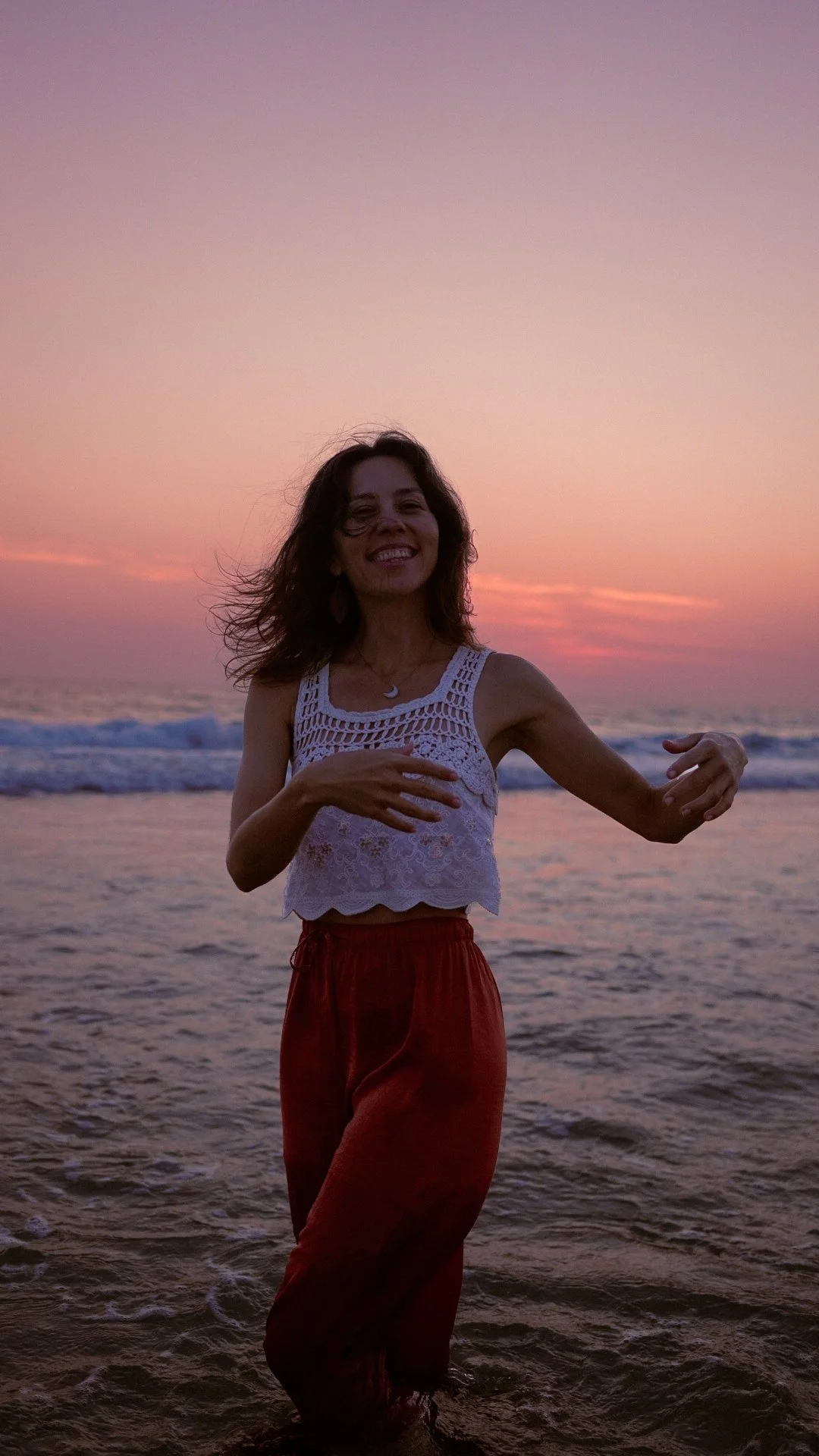 Femme dansant sur la plage au coucher du soleil