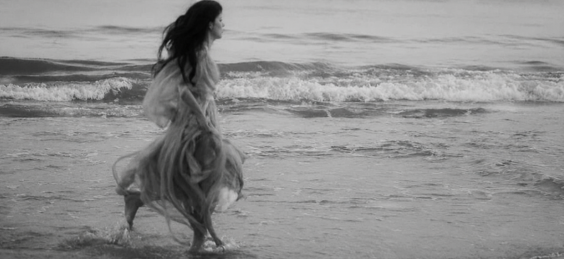 Femme marchant dans les vagues au coucher du soleil