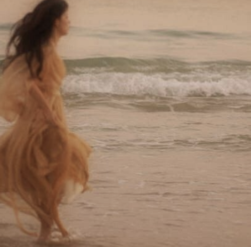 Femme marchant dans les vagues au coucher du soleil