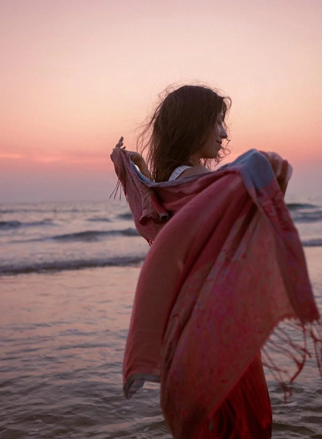 Éloïse enveloppée dans une écharpe rose, plage au coucher du soleil