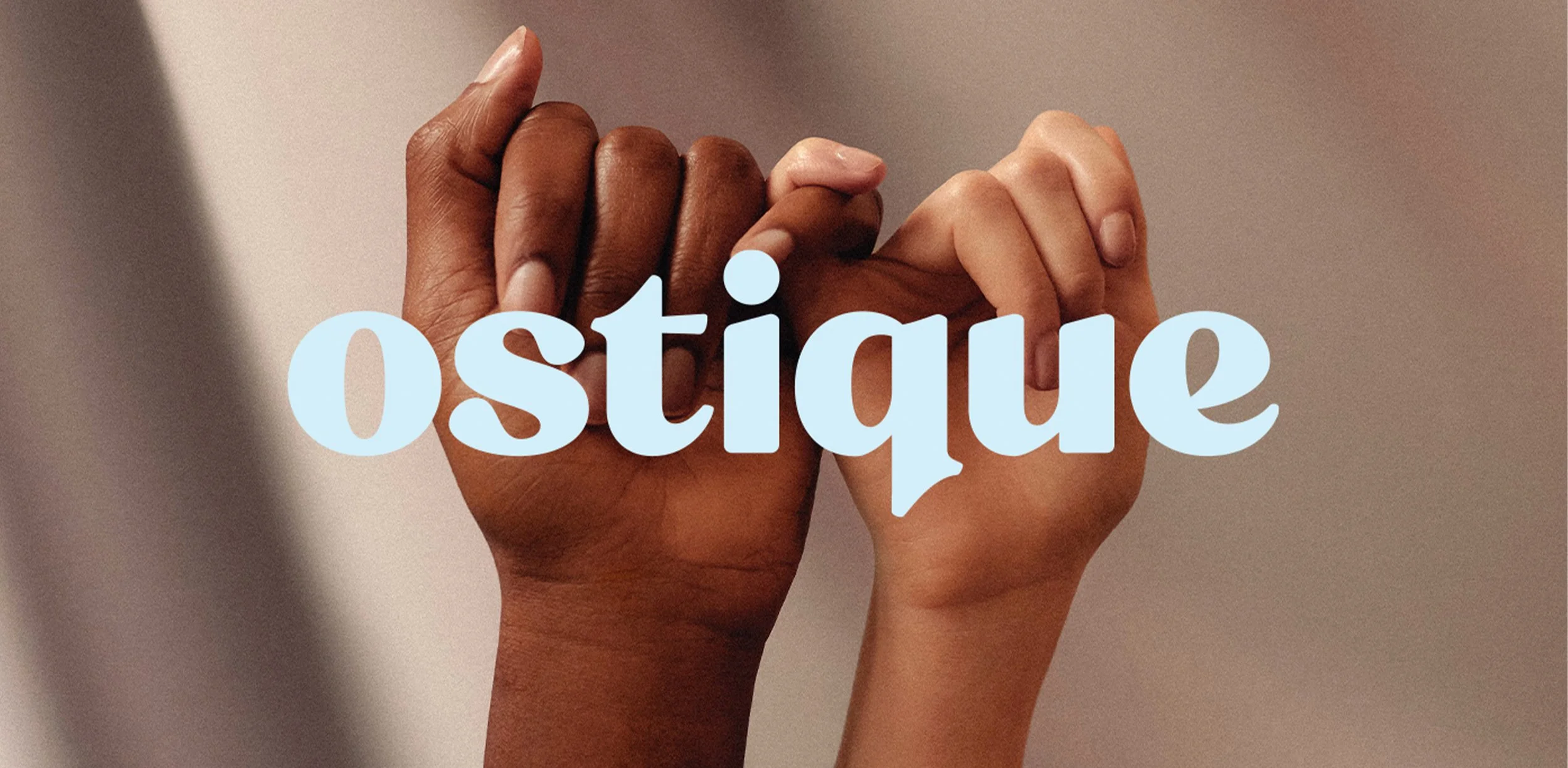Close-up of two hands, one dark-skinned and one light-skinned, holding each other with the word 'Ostiya' in light blue overlaid on the image.
