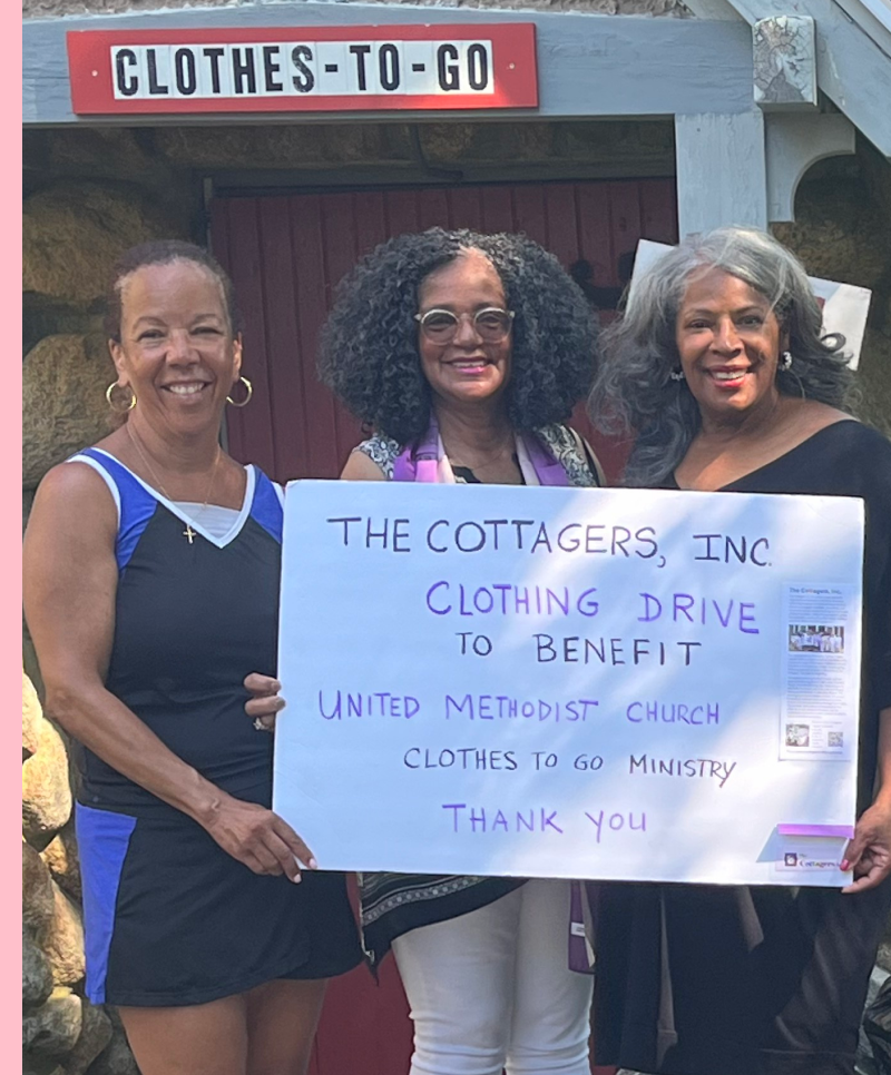 Three women smiling and holding a large sign about a clothing drive to benefit United Methodist Church. Behind them is a sign that reads 'Clothes-To-Go', indicating a clothing distribution service.
