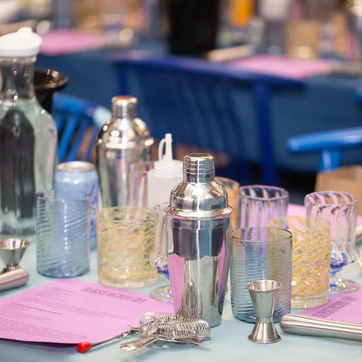 Barware on a table with cocktail shakers, glasses, and menus.