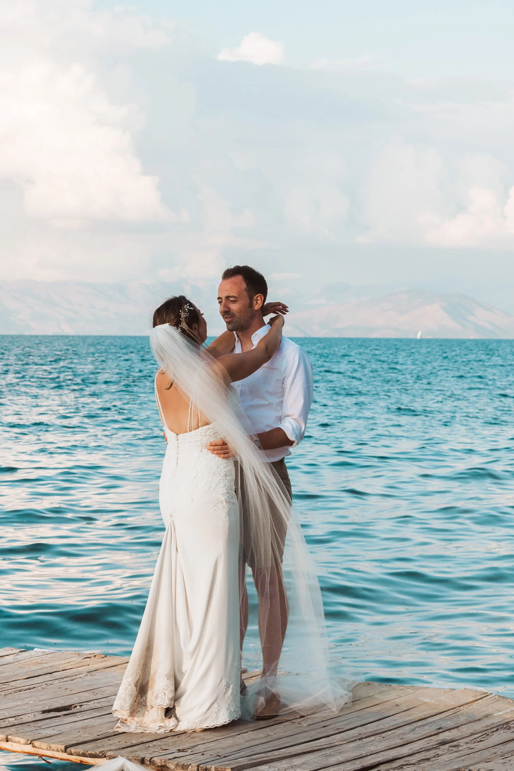 A bride and groom dancing on a wooden dock by the sea