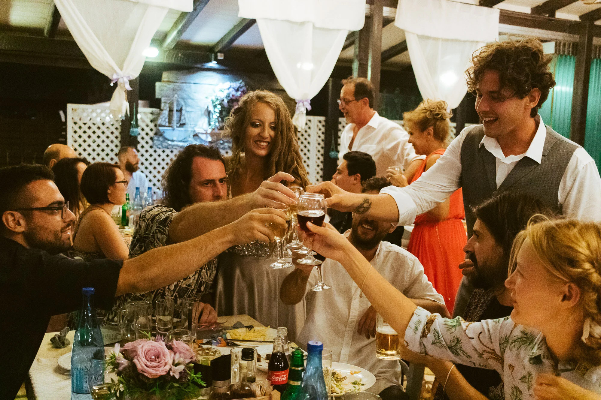 Group of friends at a celebration, raising glasses for a toast at a restaurant or banquet hall.