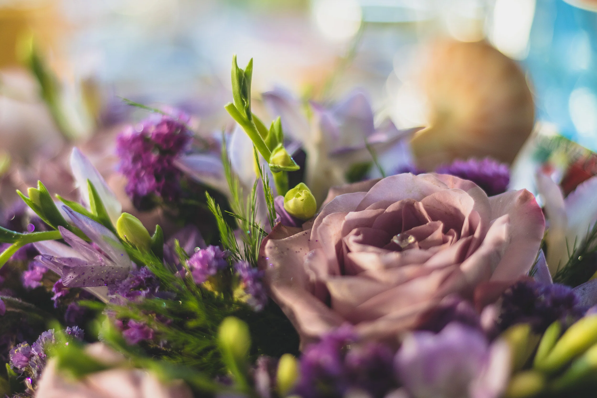 Close-up of a floral bouquet with pink roses, purple statice, and green buds.