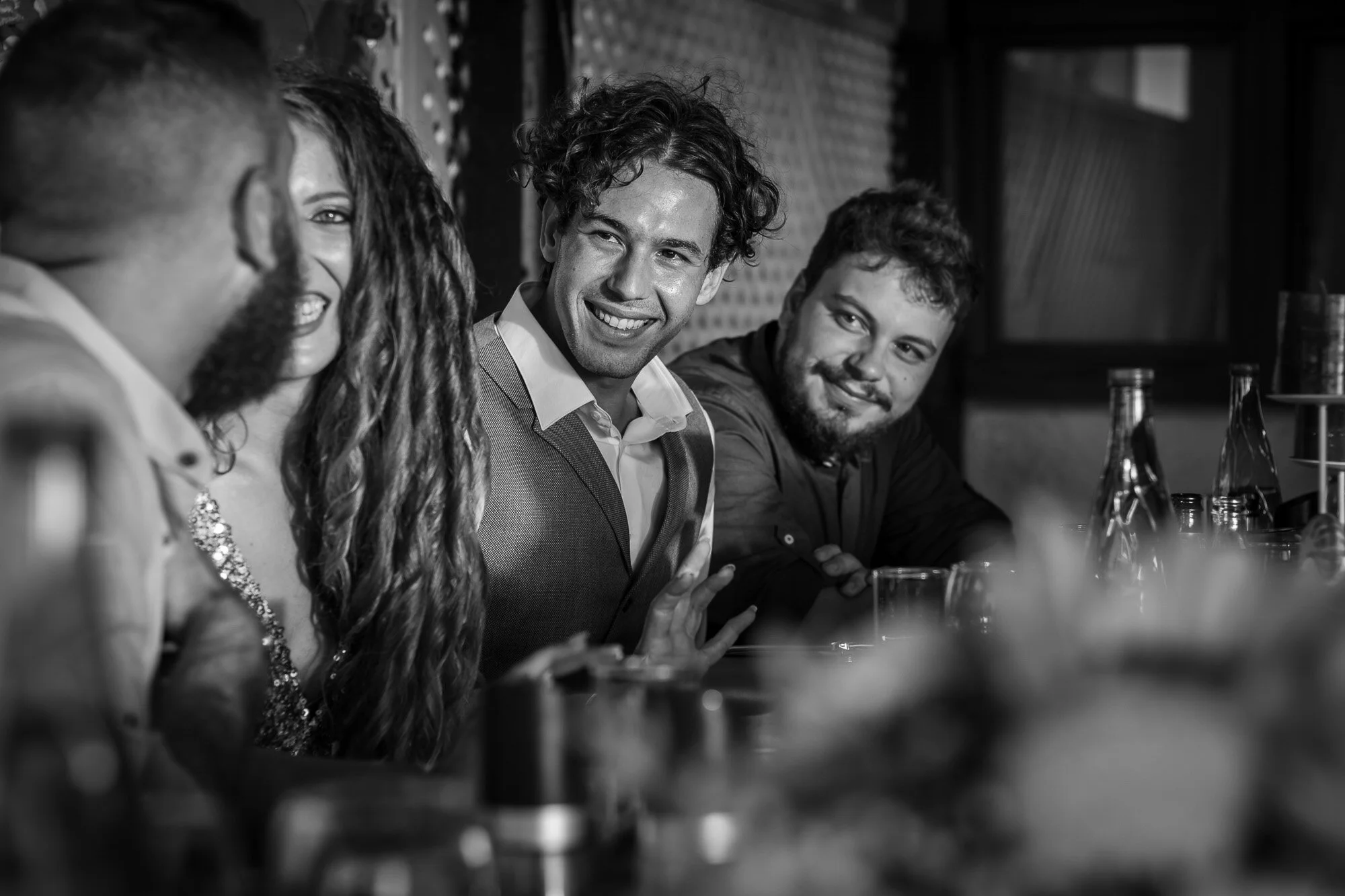 Four friends sitting at a bar, smiling and engaging in conversation.