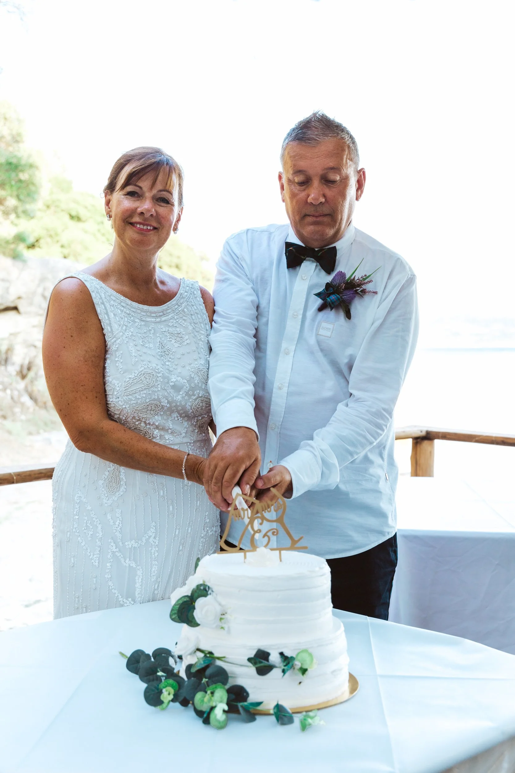 A bride and groom cutting their wedding cake outdoors during daytime.