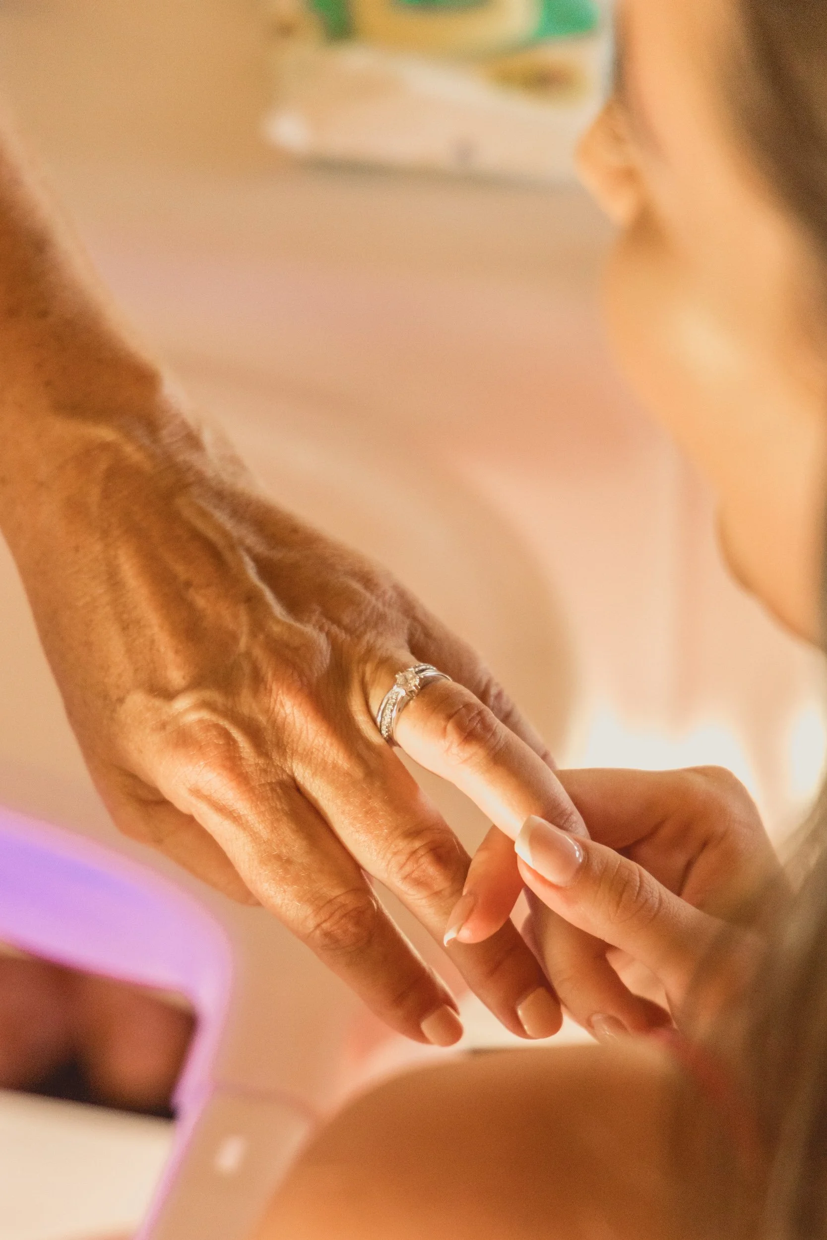 Close-up of two hands touching; one hand is adorned with a silver ring, and the other hand is gently holding the first hand.
