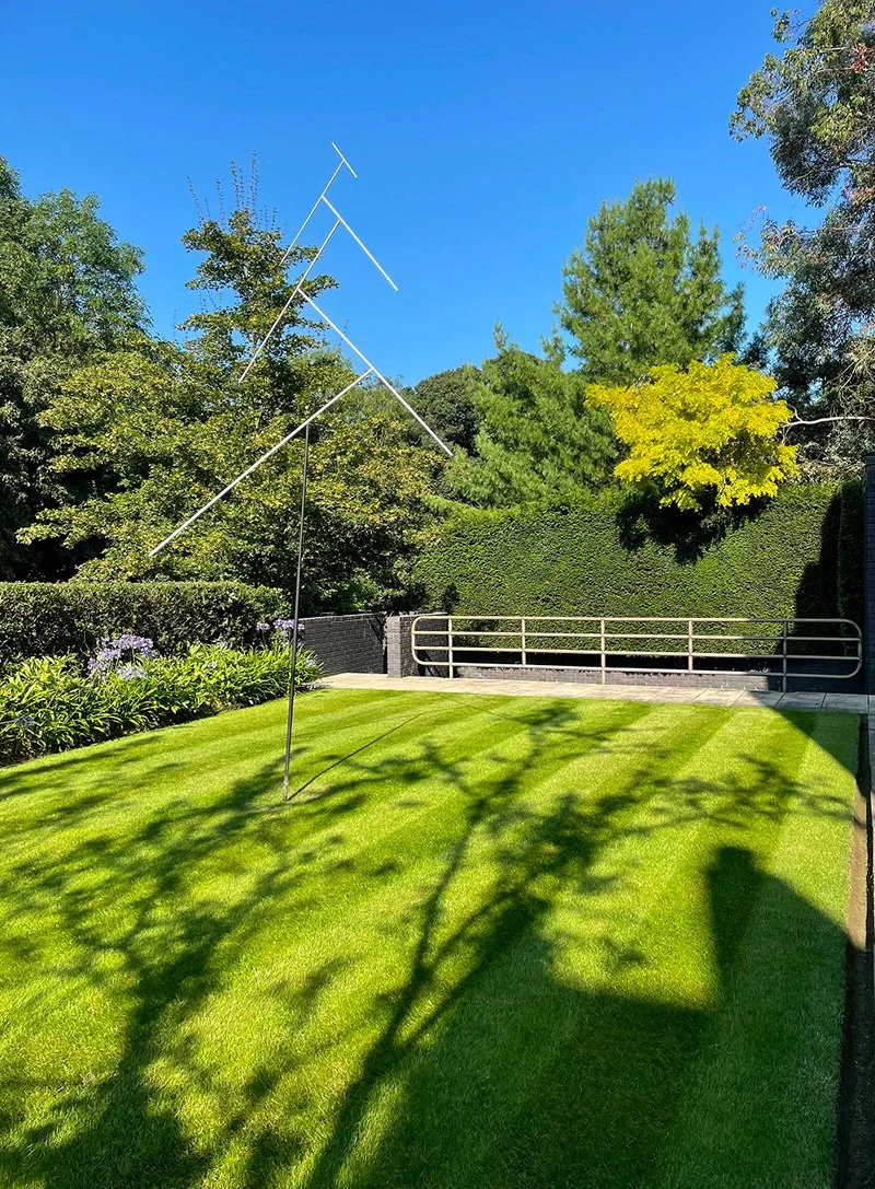 Well-maintained lawn with mature trees, borders and seasonal planting in a private garden.