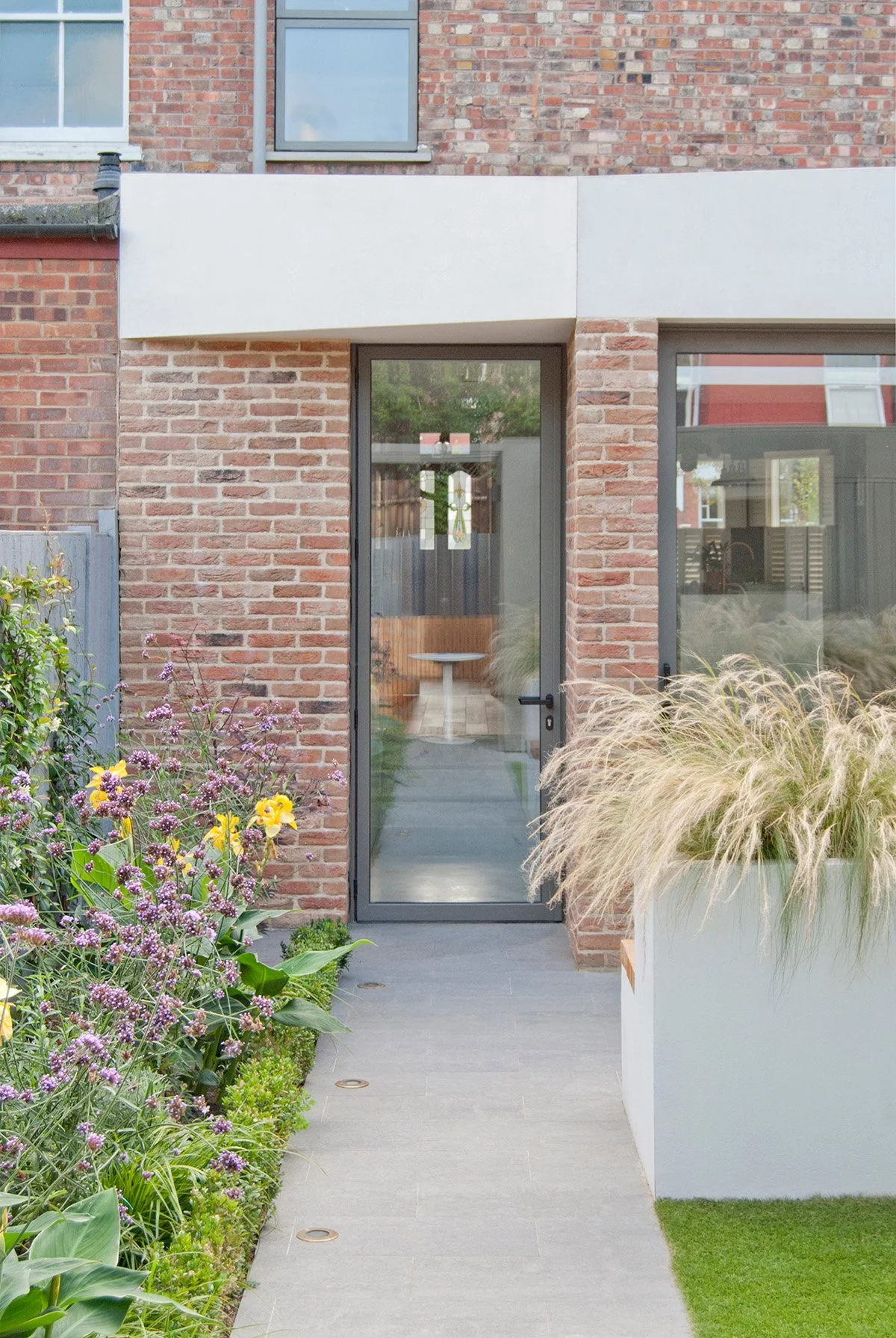 Front garden planting surrounding the entrance to a contemporary brick home.