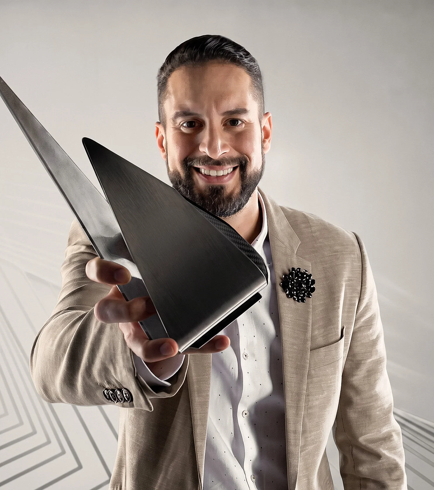 Hombre con barba y cabello oscuro sosteniendo un trofeo plateado y negro. Lleva saco beige y camisa blanca con digramas negros. Fondo gris claro.