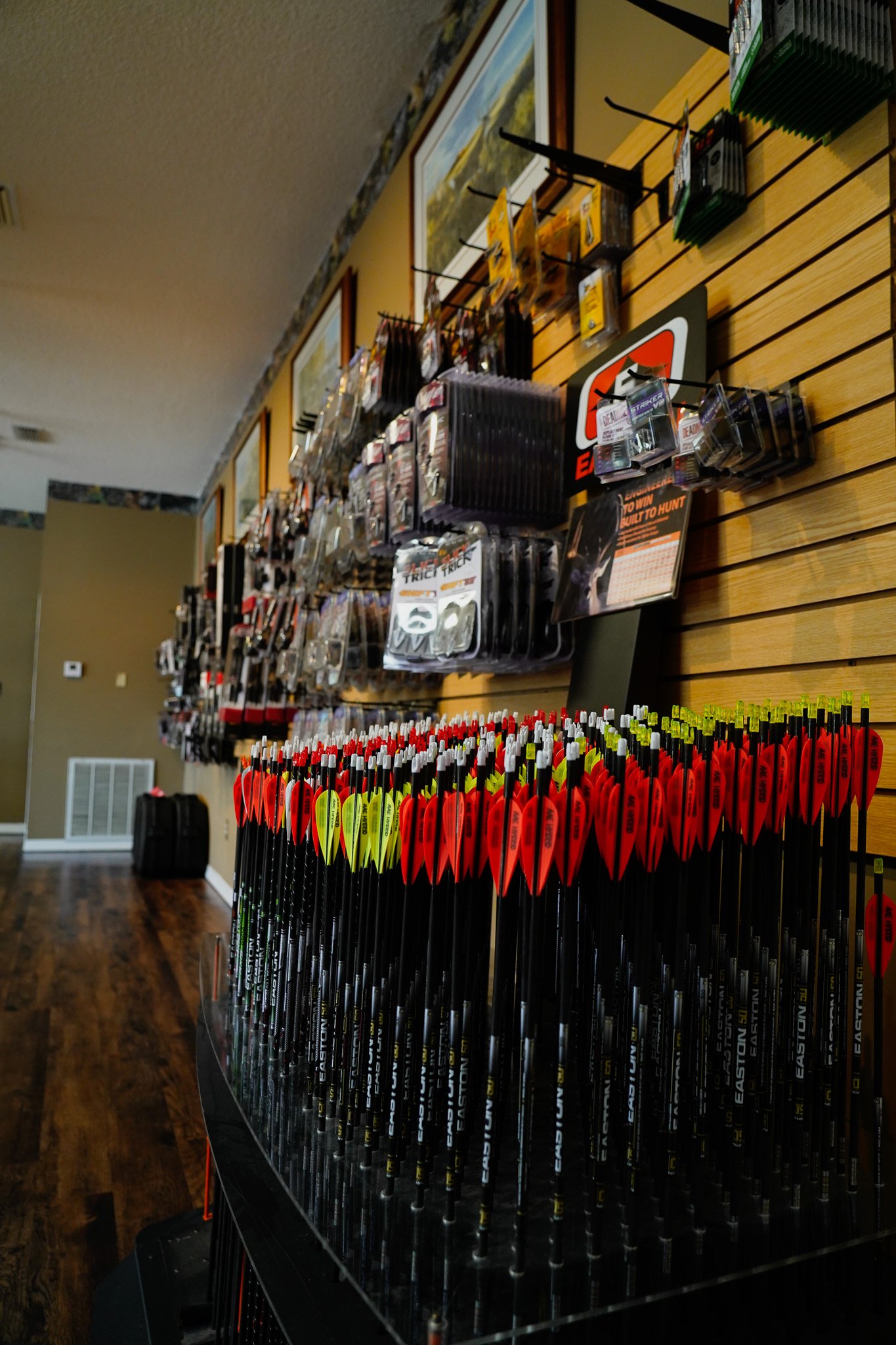 Display of multiple Easton carbon arrows with red and yellow fletching in a sporting goods store.