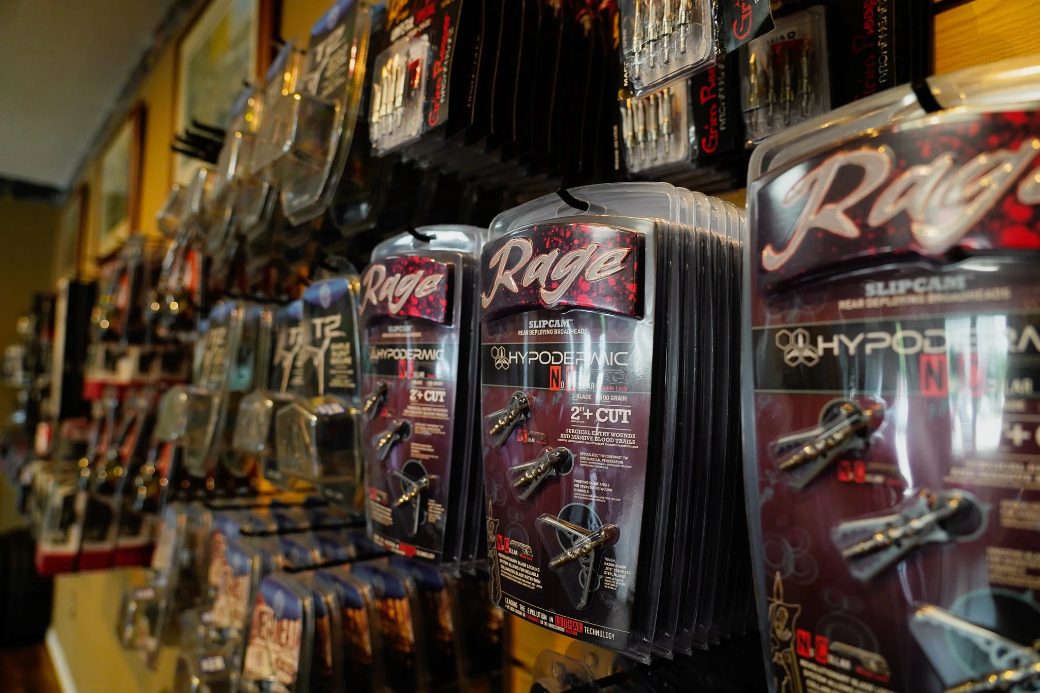 Rows of packaged Rage brand survival knives and knives for sale on a store shelf.