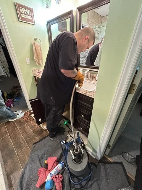 Plumber cleaning up a bathroom vanity area after a fixture service