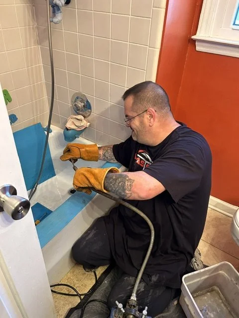 Plumber installing blue waterproof padding around a bathtub's edge