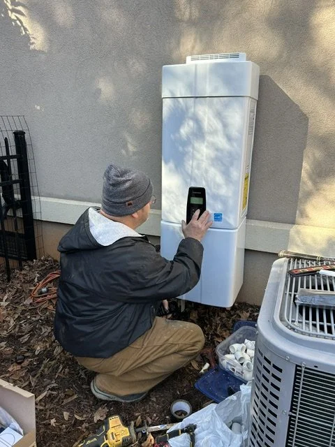 Plumber documenting an outdoor unit on site during a thorough assessment