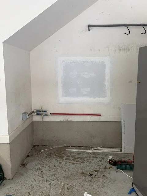 Interior wall with new plumbing pipes exposed during a repipe before drywall repair