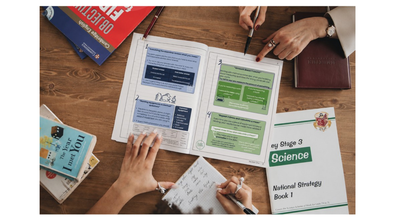 student and teacher working over a science textbook - CGP revision guide