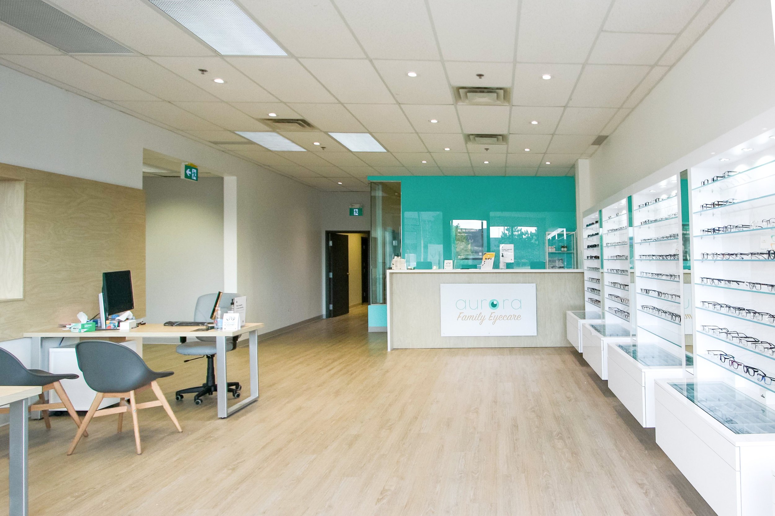 Interior of a modern eyewear store with a reception desk, display shelves with eyeglasses, and seating area.