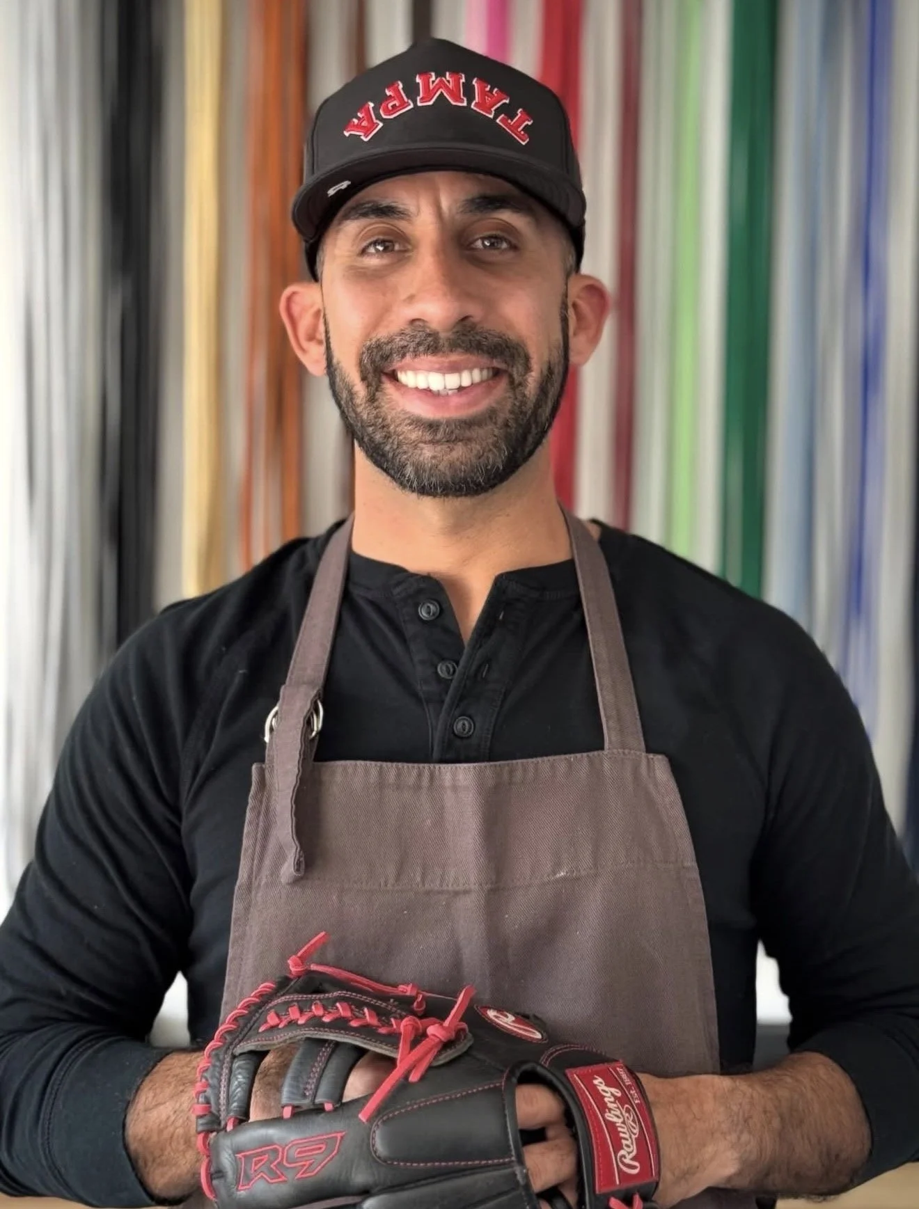Alberto, firefighter and founder of Mitt Fix Co., holding a restored baseball glove