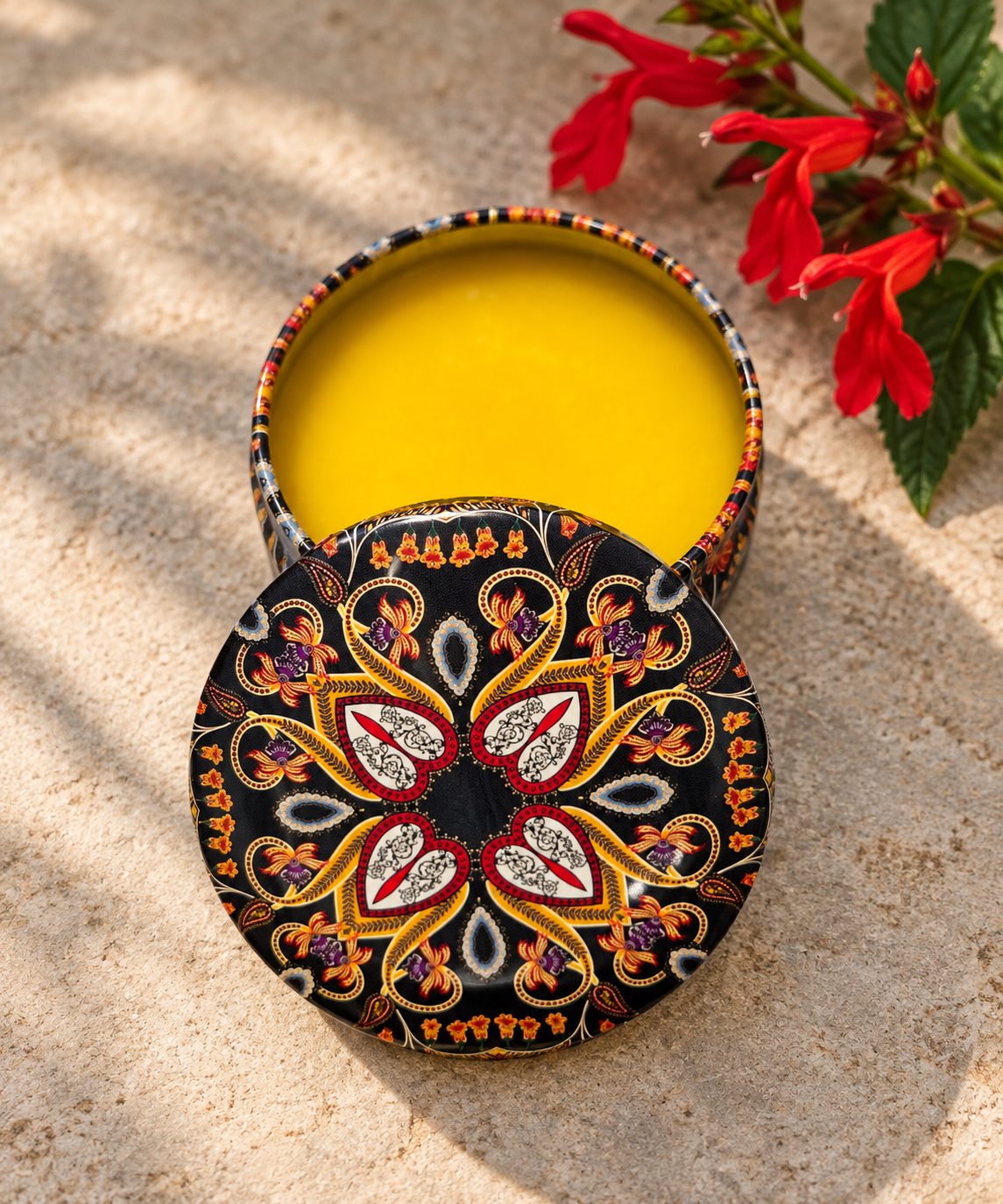 Open decorative tin of Mind Your Own Beeswax hand balm showing the golden balm inside.