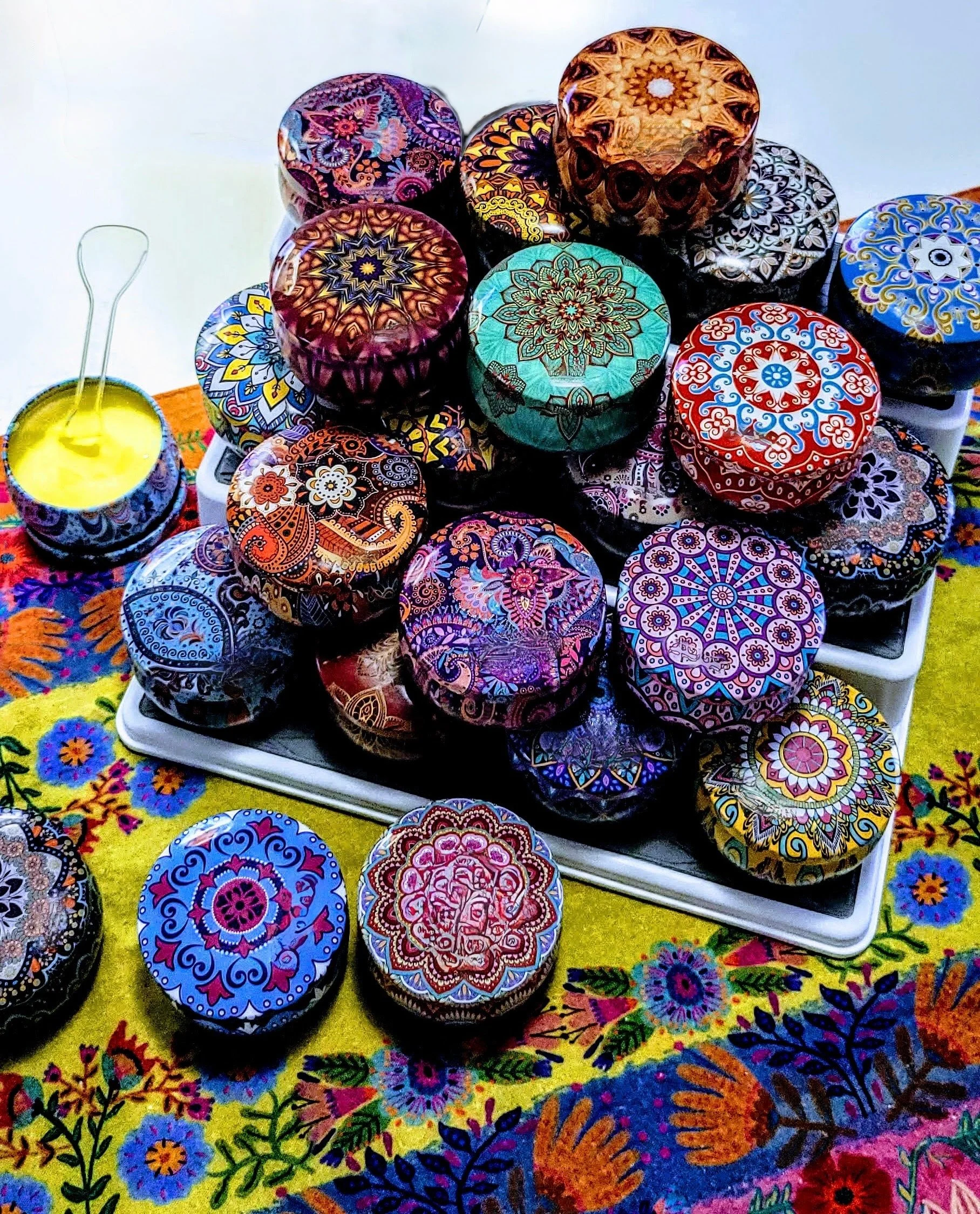 Collection of colorful decorative tins of Mind Your Own Beeswax hand balm arranged for display.