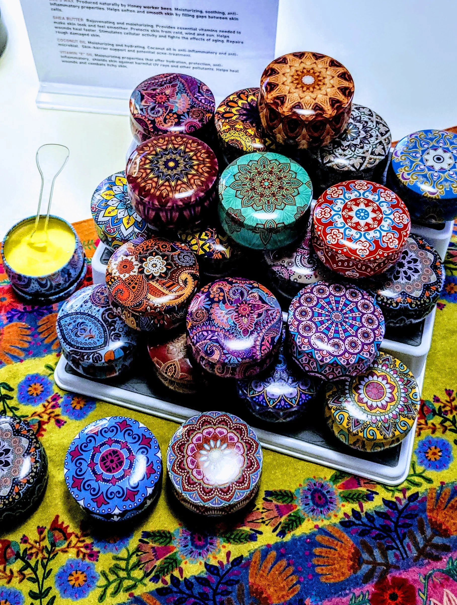 Colorful tins of Mind Your Own Beeswax hand balm arranged for retail display.