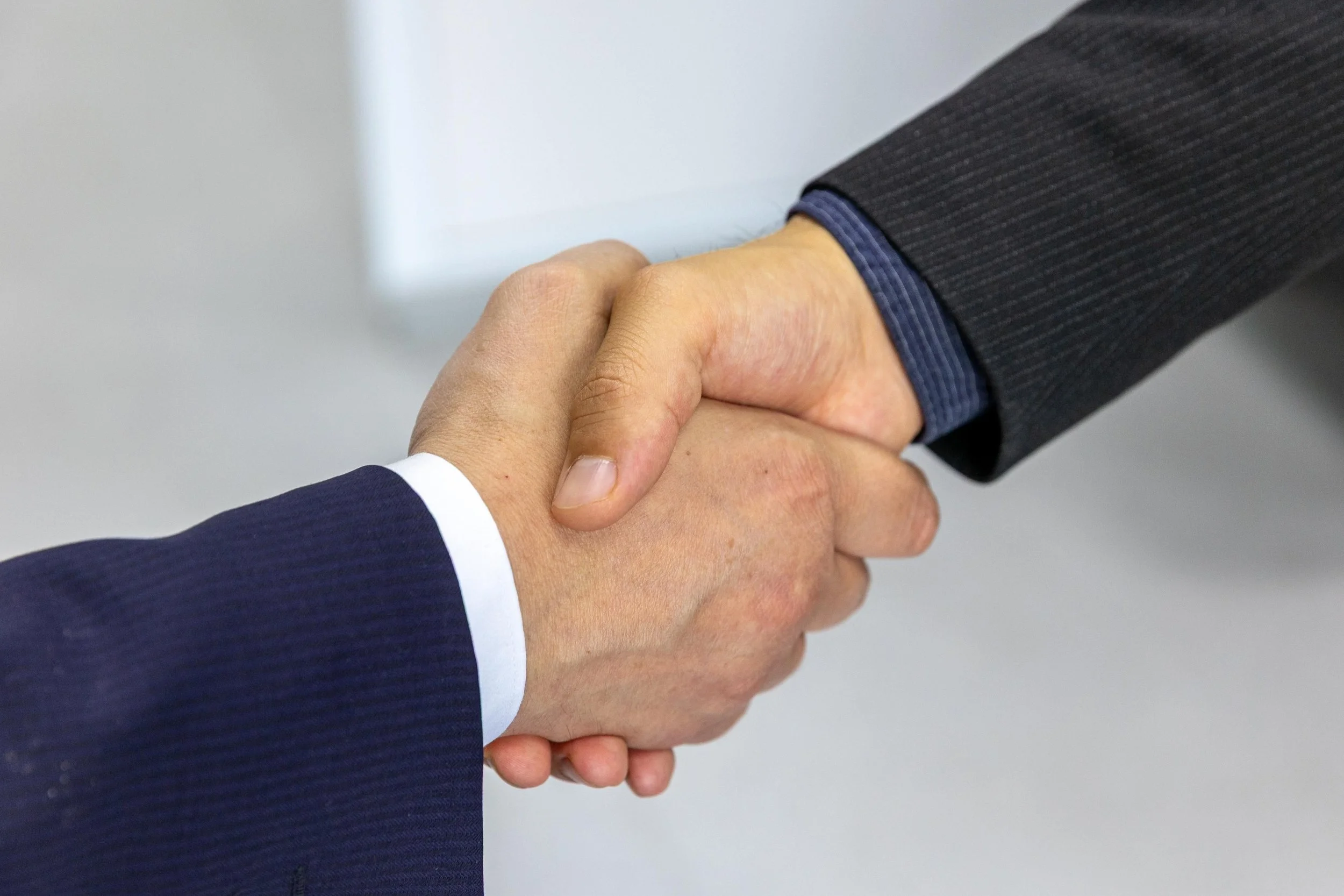 Close-up of two people in business suits shaking hands.