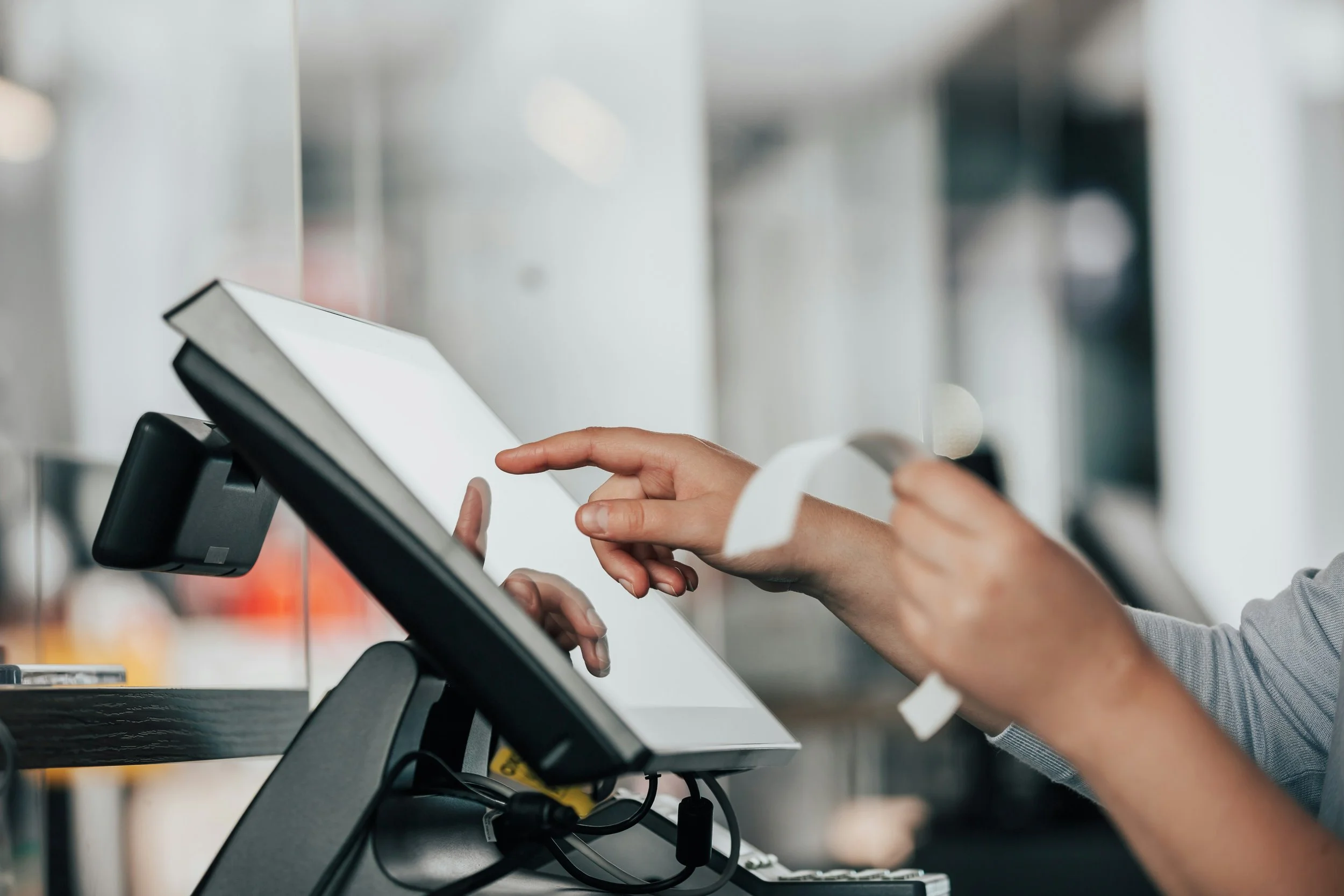 A person using a point of sale touchscreen register in a retail or checkout setting.