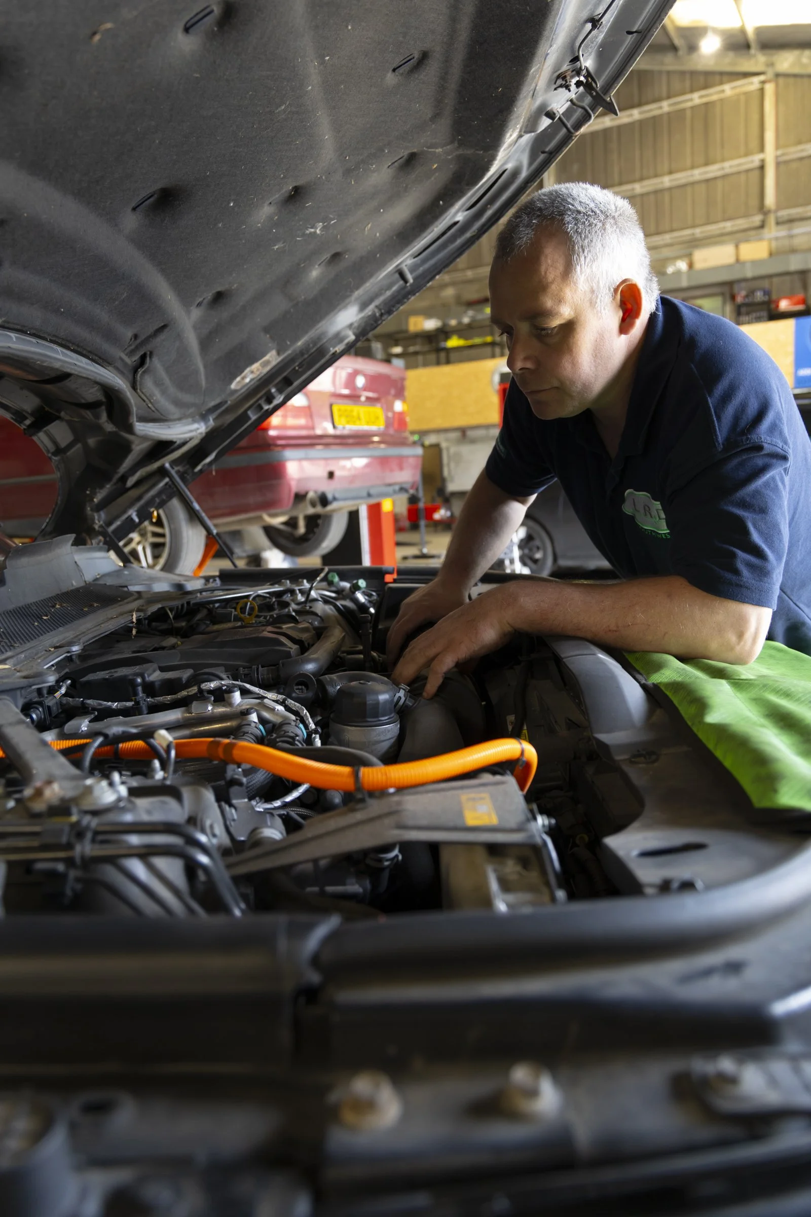 A mechanic working on a car engine inside a garage.