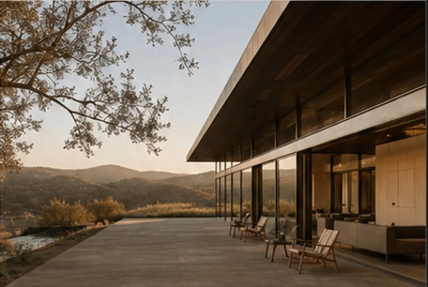 Modern house with large glass windows and an expansive outdoor patio, overlooking rolling hills and a distant mountain range during sunset.