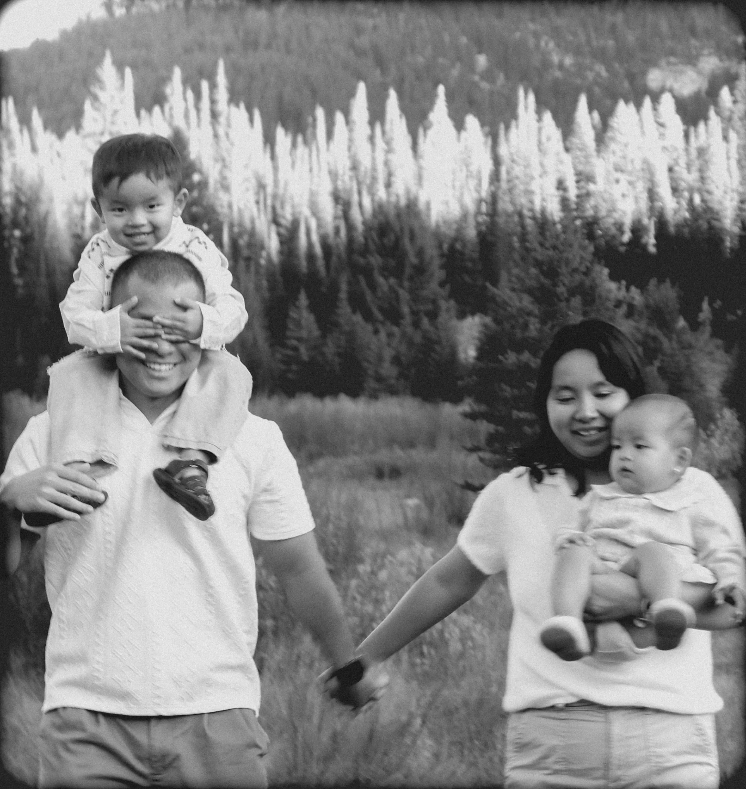 A black and white photograph of children outdoors, with a background of trees and mountains.
