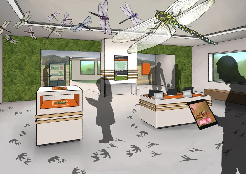 Interior of a nature or wildlife exhibit with large dragonfly models and shadow silhouettes of people, green wall, informational displays, and a tree print on an electronic tablet.