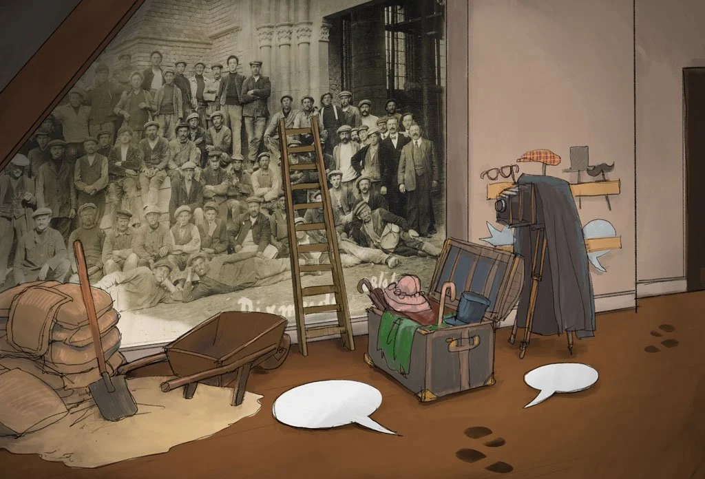A photograph of a large group of people, likely from a historical era, displayed behind a glass case in a museum. The display includes a wooden ladder, a wheelbarrow, sacks, and various vintage clothing and accessories such as hats, glasses, and a ca