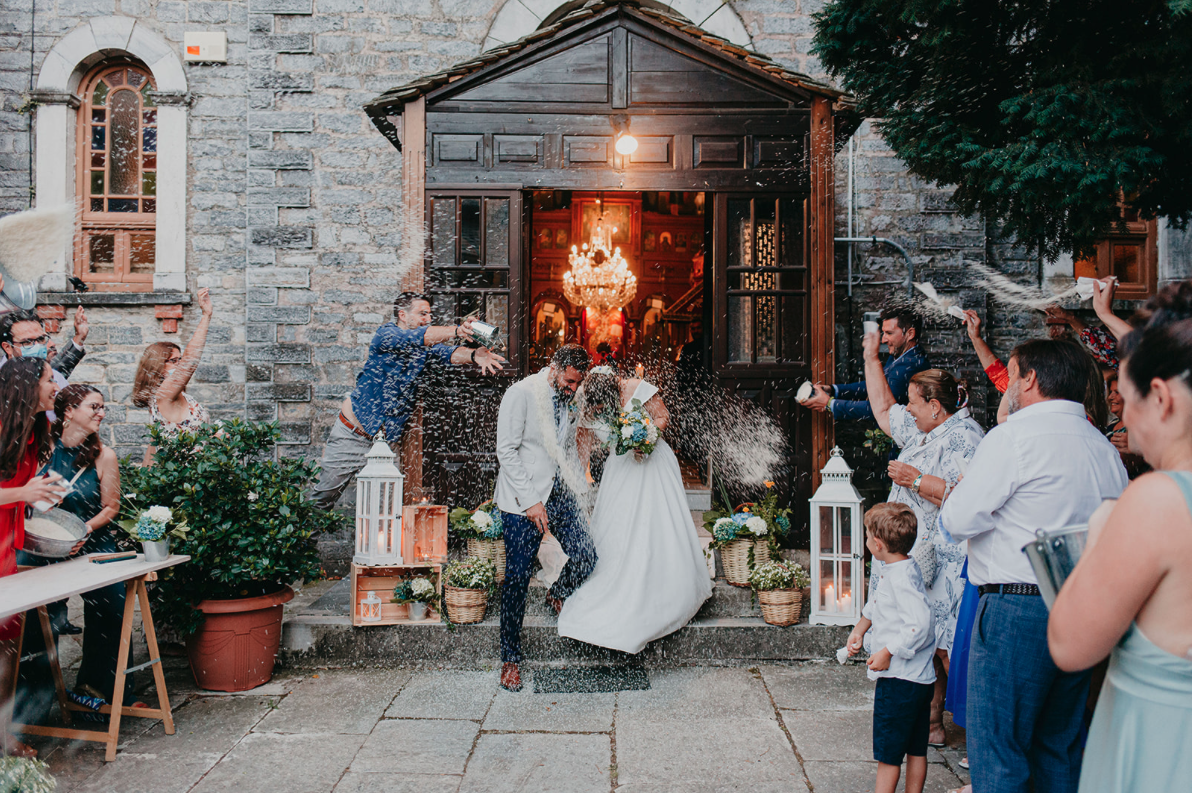 A wedding celebration outside a church with guests throwing rice at the bride and groom.