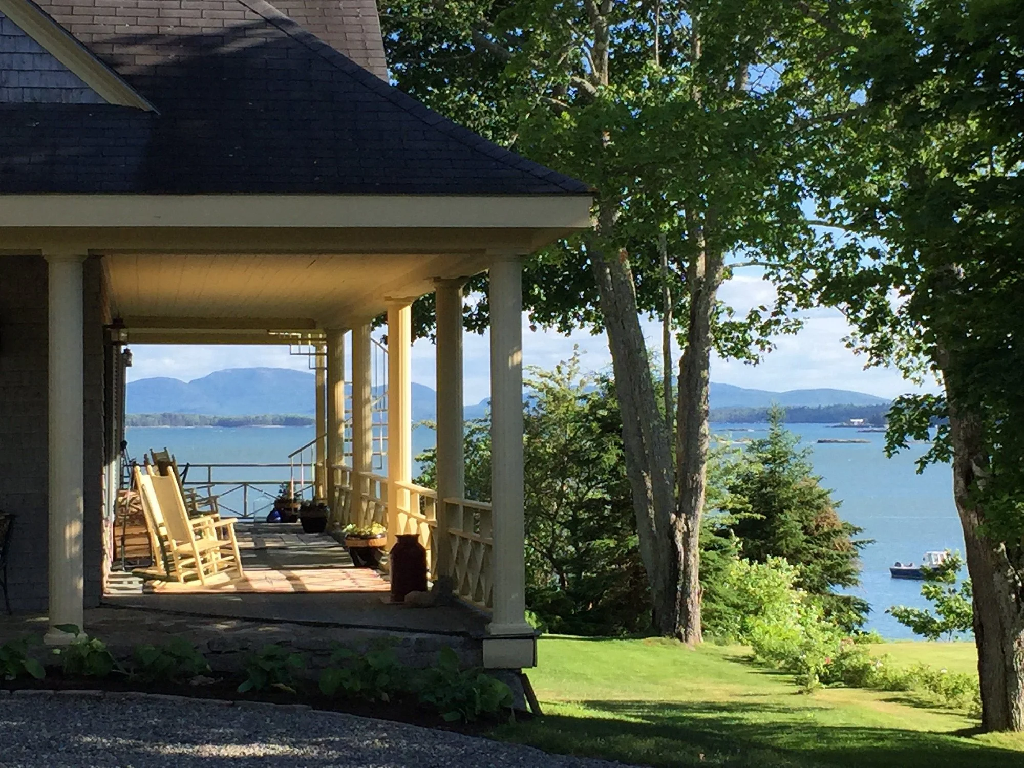 The Acadia Bay Inn Bed & Breakfast porch with rocking chairs overlooking Frenchman's Bay, Bar Harbor, and Acadia National Park in the background.