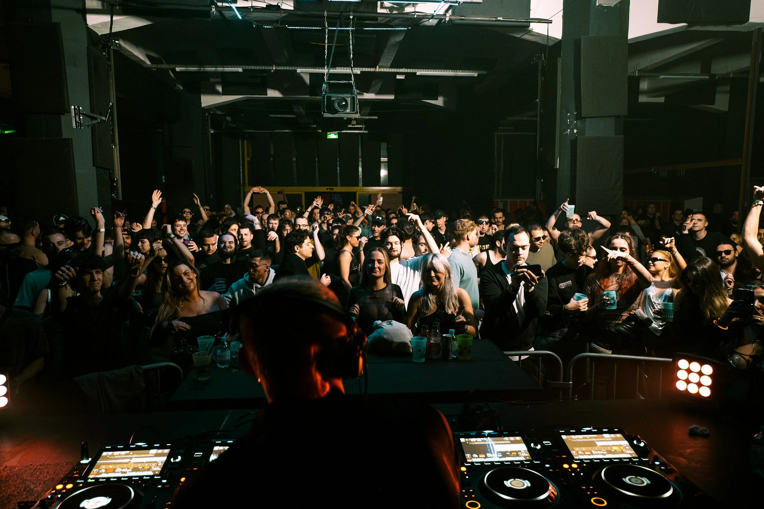 DJ overlooking a lively event crowd from behind booth