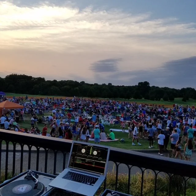 Large event crowd viewed from behind the Social Sound Co. DJ setup.