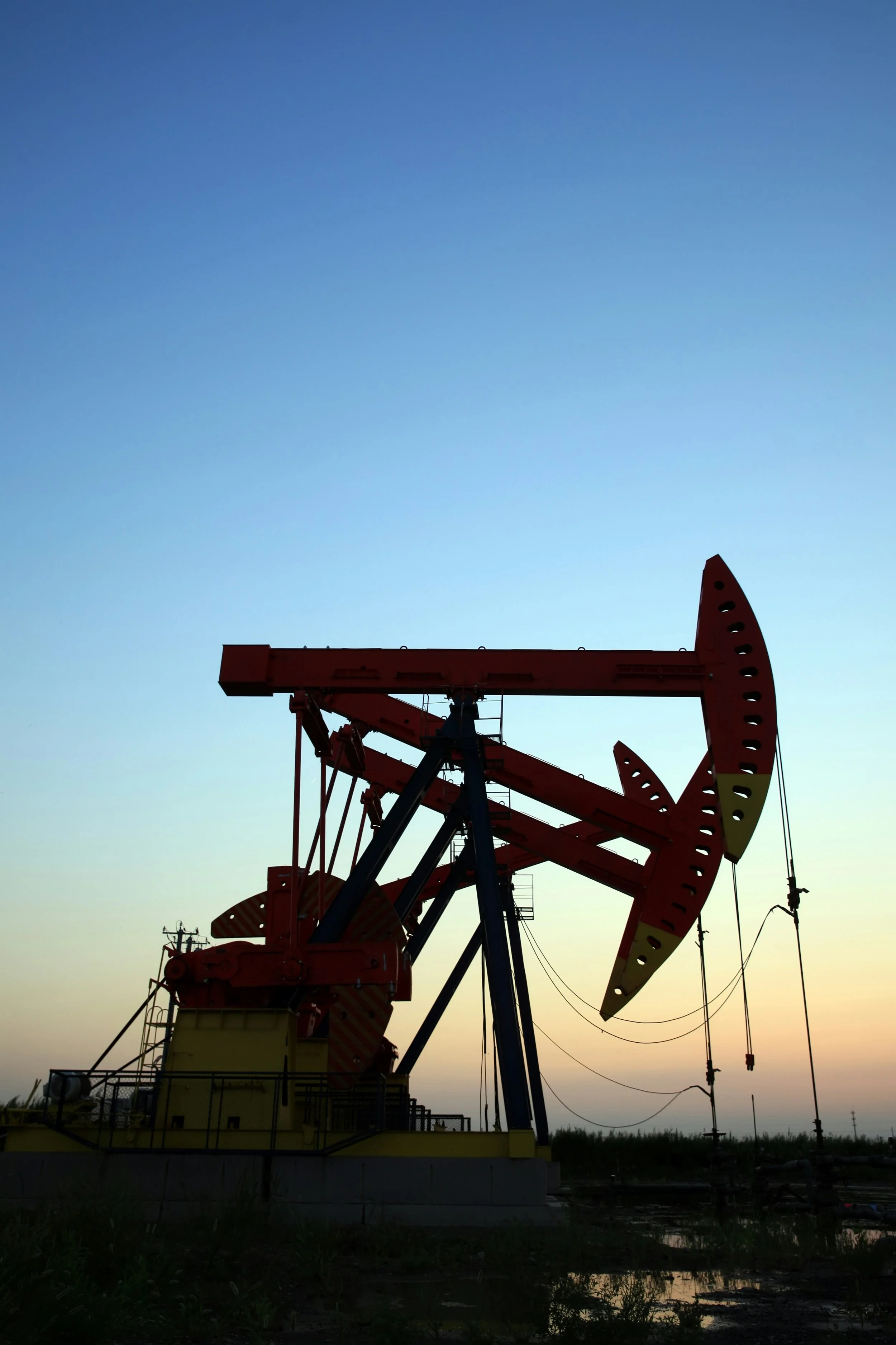 Oil pumpjack silhouetted against a dusky sky near sunset.