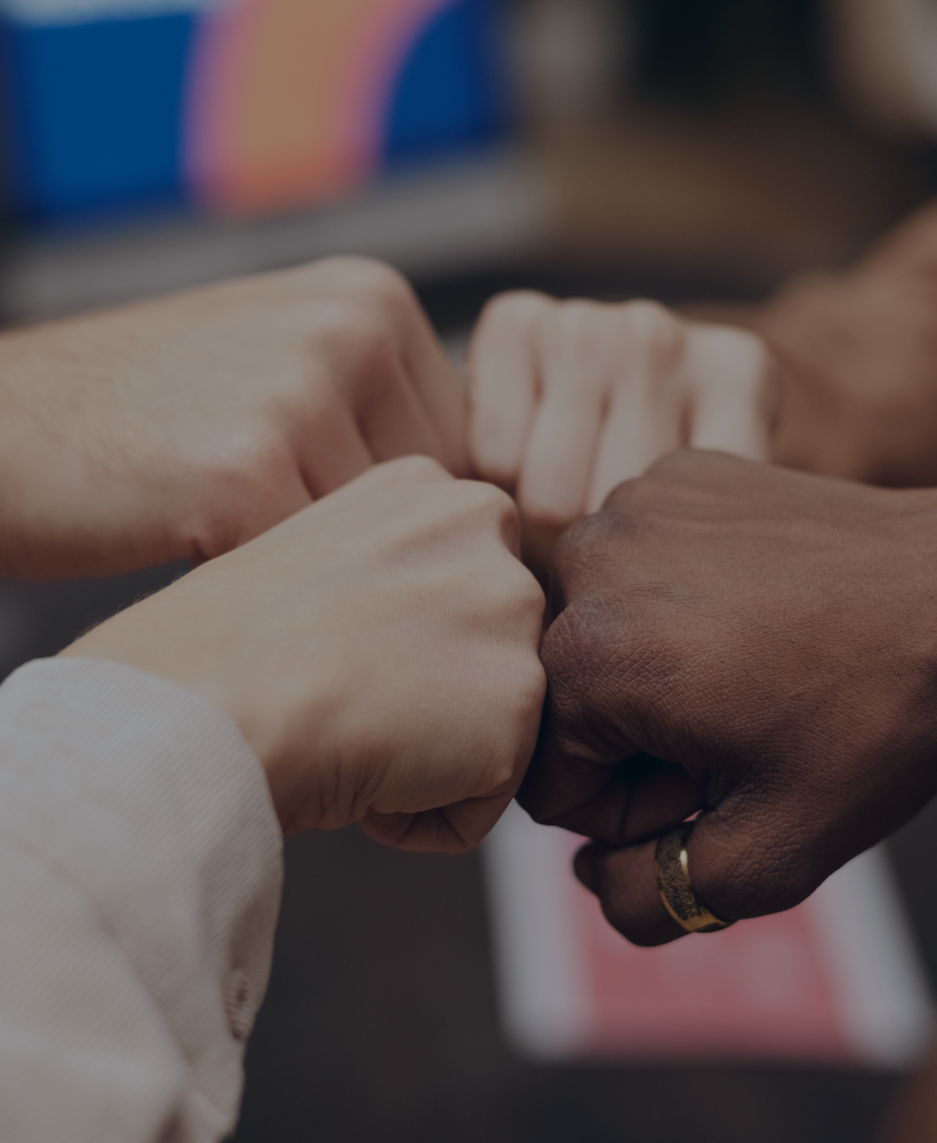 Close-up of two hands clasped together, one light-skinned and one dark-skinned, in a gesture of unity or friendship.